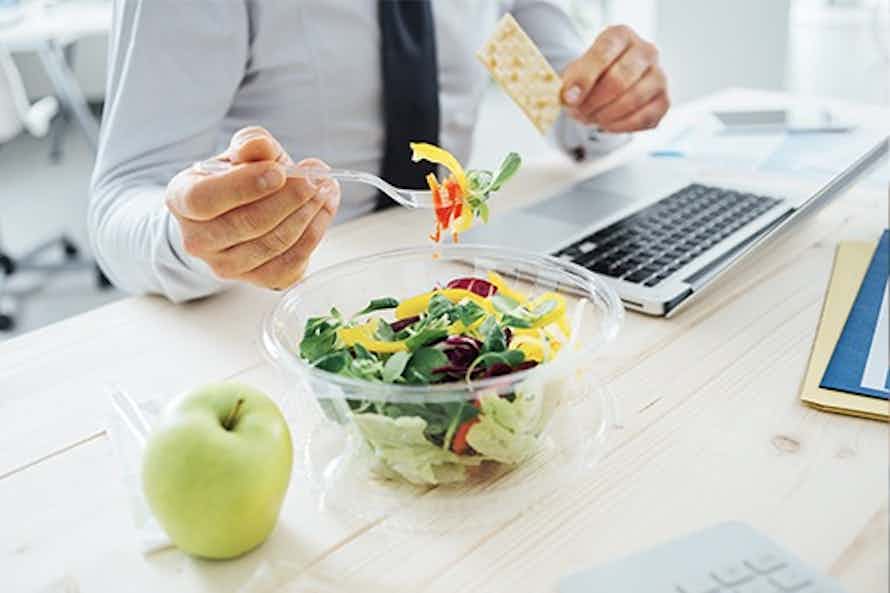 Man eating healthy at the office as part of a workplace wellness program